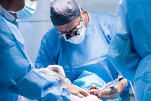 A male dentist in uniform perform dental implantation operation on a patient at dentistry office.